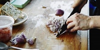 Eine Person, die eine Zwiebel mit einem Messer schneidet
